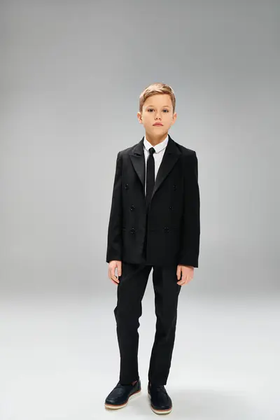 Предрожденный мальчик в остром костюме и галстуке на сером фоне. — стоковое фото