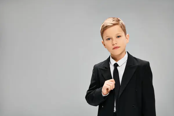 Adorable niño preadolescente en traje elegante y corbata contra fondo gris. - foto de stock
