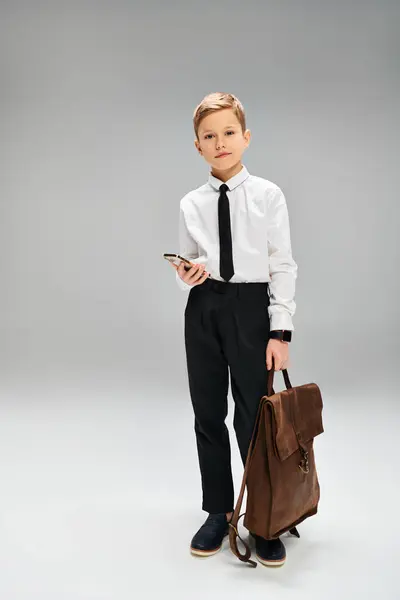 Garçon préadolescent en chemise blanche et cravate tient sac brun secret sur fond gris. — Photo de stock