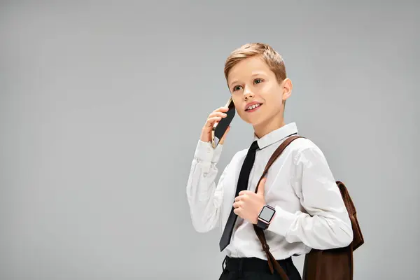 Un jeune garçon en tenue élégante tient un téléphone portable à son oreille. — Photo de stock