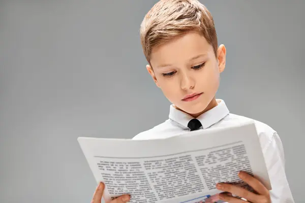 Young boy immersed in a book, dressed in a tie and looking sharp. — Stock Photo