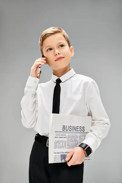 A preadolescent boy in business attire holding a newspaper. — Stock Photo