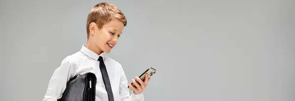 Kleiner Junge in weißem Hemd und Krawatte, selbstbewusst in der Hand ein Handy. — Stockfoto