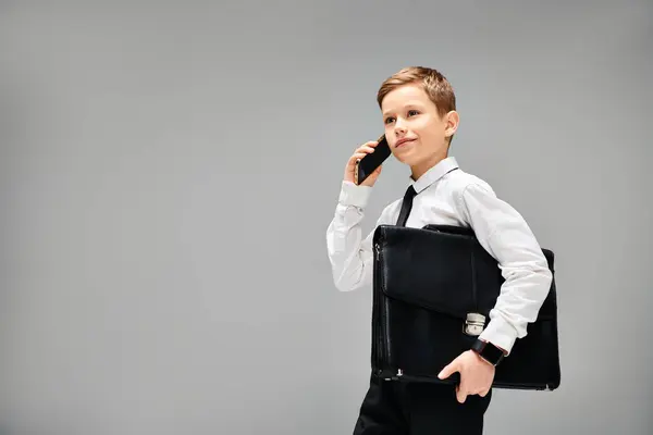 A stylish boy holds a briefcase and talks on a cell phone. — Stock Photo