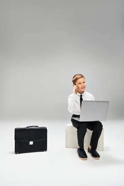Young boy in elegant attire sits on stool, engrossed in laptop. — Stock Photo