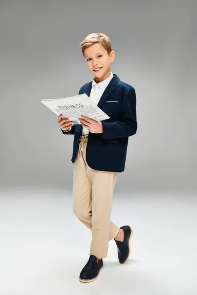 Опрятный мальчик в синем пиджаке и брюках цвета хаки, погружённых в чтение. — стоковое фото