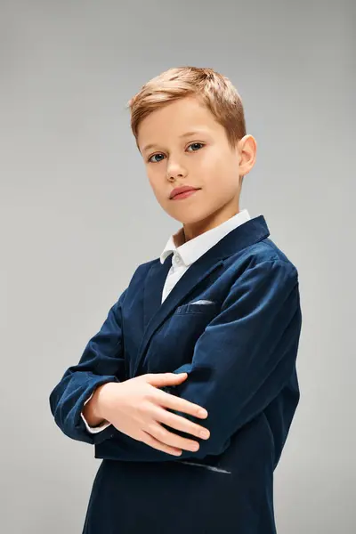 Preadolescent boy in elegant blue suit standing with arms crossed. — Stock Photo
