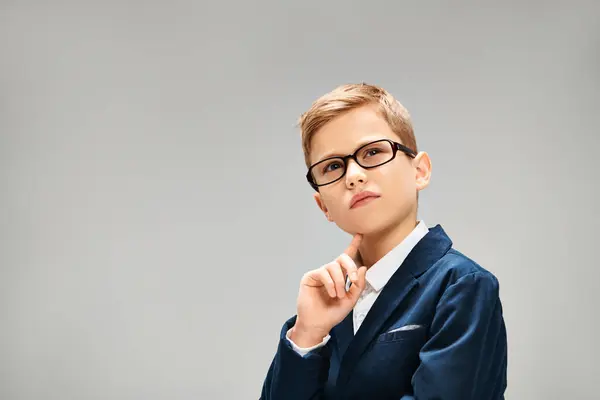 Hombre joven en gafas y chaqueta azul sobre fondo gris. - foto de stock
