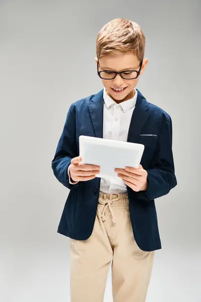 Um menino de terno e óculos, segurando um tablet, encarna o futuro dos negócios. — Fotografia de Stock