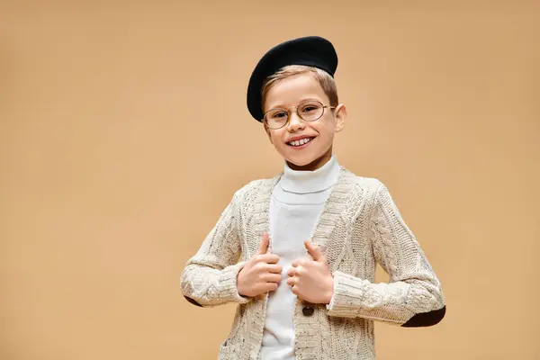 Un niño preadolescente en gafas y un sombrero da un pulgar hacia arriba, vestido como un director de cine. - foto de stock