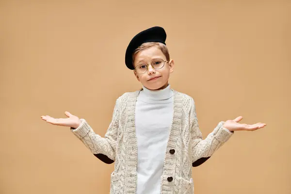 Um menino pré-adolescente bonito em óculos e um chapéu, vestido como um diretor de cinema em um cenário bege. — Fotografia de Stock