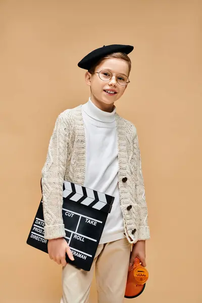 Young boy in glasses and a sweater holds a clapper. — Stock Photo