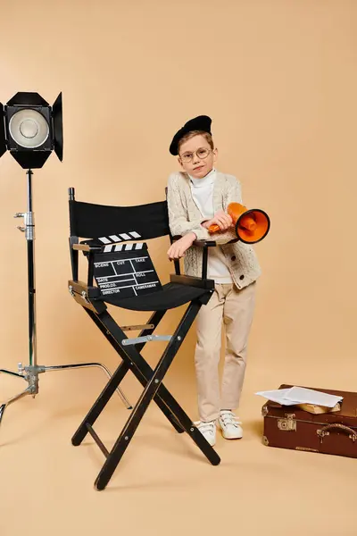 Маленький хлопчик з гордістю стоїть біля стільця режисерів. — стокове фото