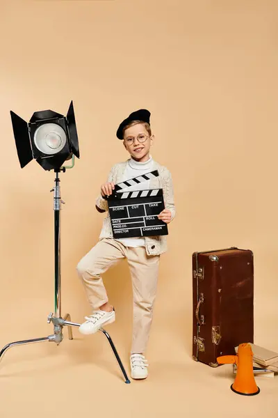 Ein Junge inszeniert eine Filmszene mit einem Klöppel vor der Kamera. — Stockfoto