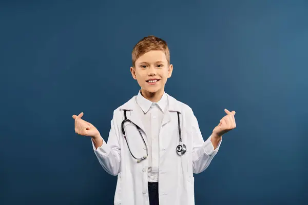 Young boy in doctors coat and stethoscope on blue backdrop. — Stock Photo