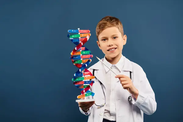 A cute preadolescent boy, dressed as a doctor, holds a model of a structure with curiosity. — Stock Photo