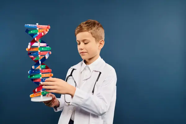 Preadolescent boy dressed as doctor holds intricate model of a structure. — Stock Photo