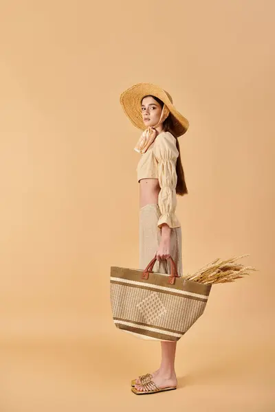 Eine junge Frau mit langen brünetten Haaren posiert im Sommer-Outfit, trägt einen Strohhut und hält einen Korb in der Hand. — Stockfoto
