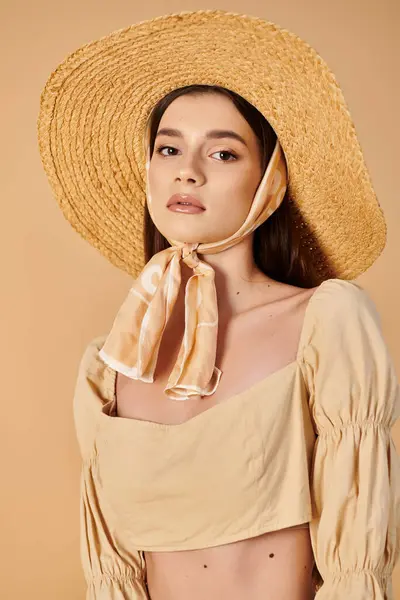 A young woman with long brunette hair strikes a pose in a summer outfit, wearing a stylish straw hat and a flowing scarf. — Stock Photo