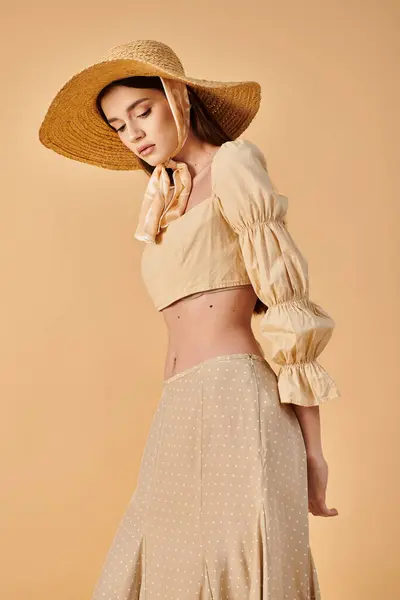 Une jeune femme à la mode avec de longs cheveux bruns frappant une pose dans un chapeau et une jupe élégantes, respirant une ambiance estivale dans un cadre de studio. — Photo de stock