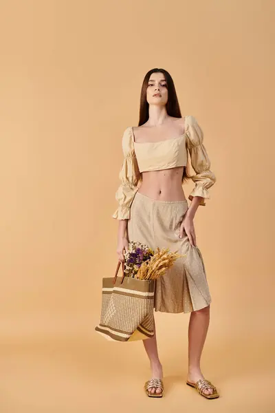 A young woman with long brunette hair poses confidently in a crop top and skirt, holding a basket with a summer vibe. — Stock Photo