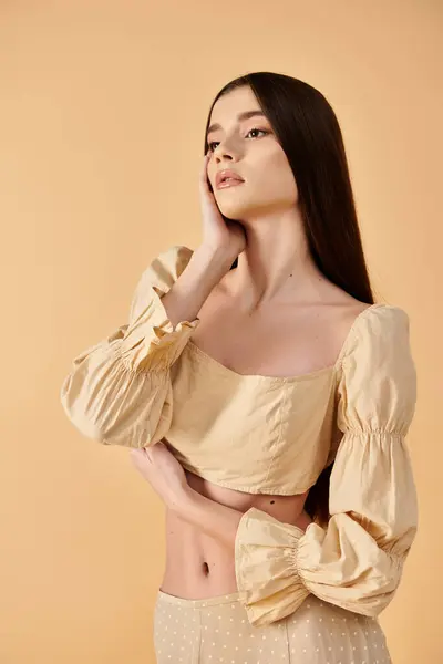 Молодая женщина с длинными брюнетками уверенно позирует в ярко-желтом топе, источая яркое летнее настроение в студии. — стоковое фото
