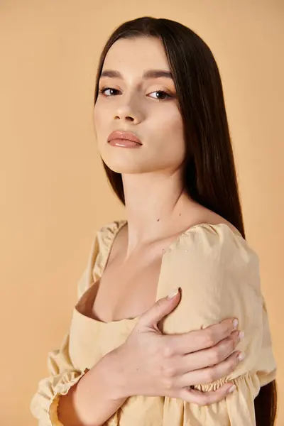 Une jeune femme aux longs cheveux bruns pose élégamment dans une robe fluide exsudant une ambiance estivale radieuse dans un décor de studio. — Photo de stock