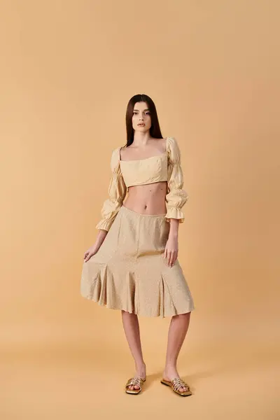 Une jeune femme aux longs cheveux bruns pose dans une tenue estivale composée d'une jupe et d'un haut de culture, respirant une ambiance estivale vibrante. — Photo de stock