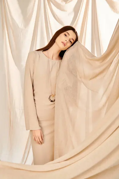 Una joven con el pelo largo y morena posa en un estudio, exudando un estado de ánimo veraniego sobre un telón de fondo de cortina blanca. - foto de stock