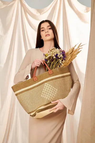 Una joven con el pelo largo morena, vestida con un traje de verano, sosteniendo una cesta llena de flores de colores. - foto de stock