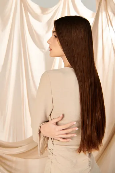 Eine junge Frau mit langen brünetten Haaren steht selbstbewusst vor einem Vorhang und verkörpert in ihrem stylischen Outfit sommerliche Stimmung. — Stockfoto