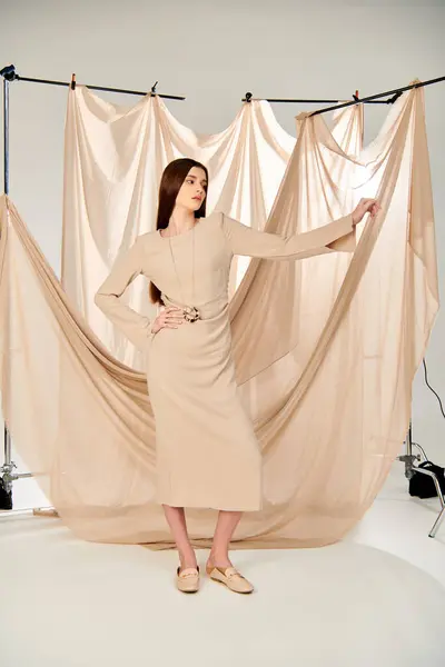 Uma jovem com cabelos longos e morena faz uma pose confiante na frente de uma cortina, com as mãos nos quadris.. — Fotografia de Stock