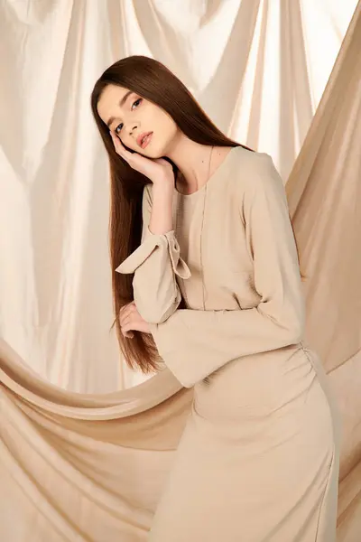 A young woman with long brunette hair strikes a pose in a beige dress, exuding summer elegance. — Stock Photo