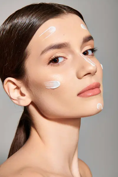 A young brunette woman poses with a generous amount of cream on her face, exuding beauty and luxury. — Stock Photo