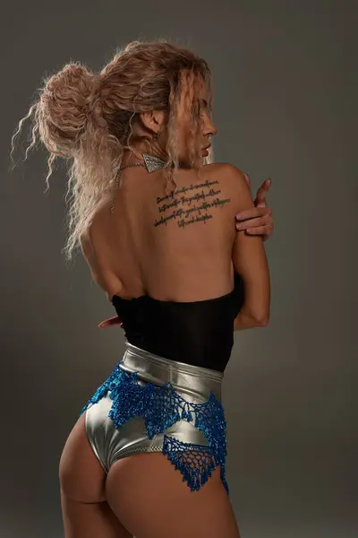 A seductive young woman with a tattoo on her back posing alluringly. — Stock Photo