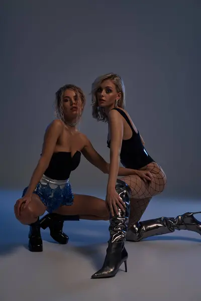 Two sexy young women strike a pose, clad in short shorts and boots, exuding confidence and style. - foto de stock