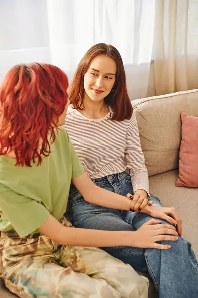 Felice coppia lgbt condividere un momento tenero su un accogliente divano in soggiorno, due giovani donne lesbiche — Foto stock