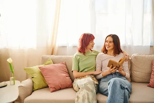 Happy lesbian couple with book enjoying quiet moment and looking at each other, love and comfort — Stock Photo