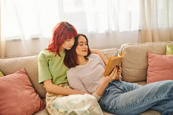 Relajada pareja lgbt disfrutar de un momento tranquilo de lectura juntos, envueltos en el amor y la comodidad - foto de stock