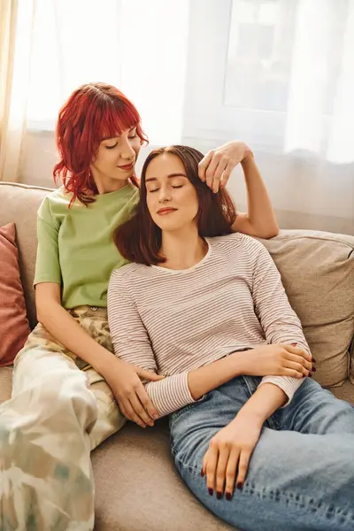 Happy young lesbian couple in her 20s enjoying time together while resting on sofa in living room — Stock Photo
