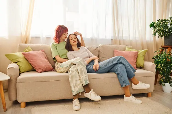 Young lesbian couple in her 20s enjoying time together while resting on sofa in living room, bliss — Stock Photo