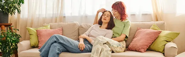 Young lesbian couple in her 20s enjoying time together while resting on sofa in living room, banner — Photo de stock