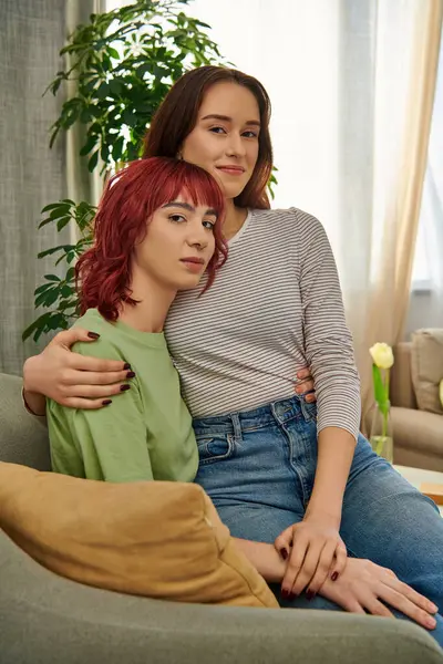 Glückliche lesbische Frau in den 20ern, die auf dem Schoß ihrer Freundin sitzt, während sie zusammen im Wohnzimmer liegt — Stockfoto
