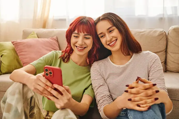 Happy lesbian couple smiling and using smartphone together, modern lifestyle and social media — Stock Photo