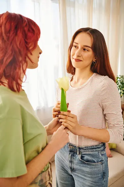 Tender moment of lesbian couple, happy woman gifting tulip to her partner, symbol of spring love — Stock Photo