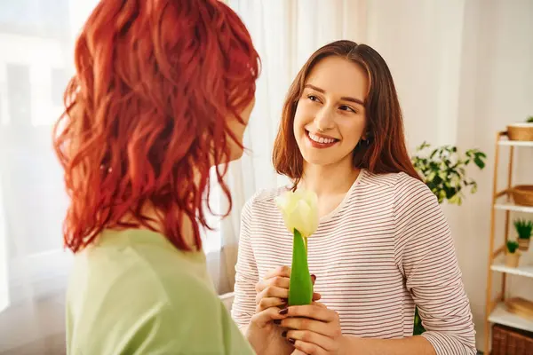 Tender moment of lesbian couple, woman gifting tulip to her happy girlfriend, symbol of spring love — Stock Photo
