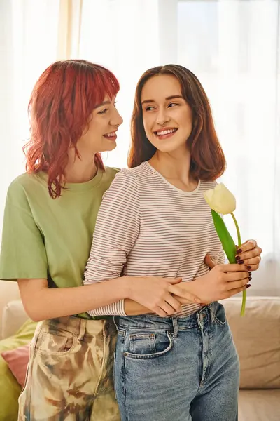 Tender moment of lesbian woman holding tulip and hugging happy girlfriend, symbol of spring and love — Stock Photo