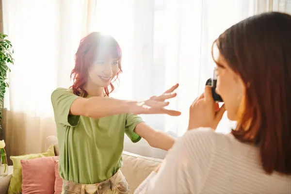 Playful photo session at home of young lesbian woman capturing her girlfriend cheerful pose — Foto stock