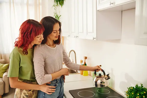 Acogedora escena doméstica de una pareja lesbiana haciendo té, un simple momento de contenido de unión - foto de stock