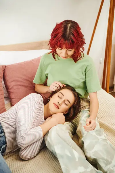 Jeune couple lesbien partageant un moment tendre, femme allongée sur des tours sur sa petite amie dans la chambre — Photo de stock